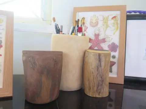 Two lidded wooden pots, with a pot of paintbrushes between them