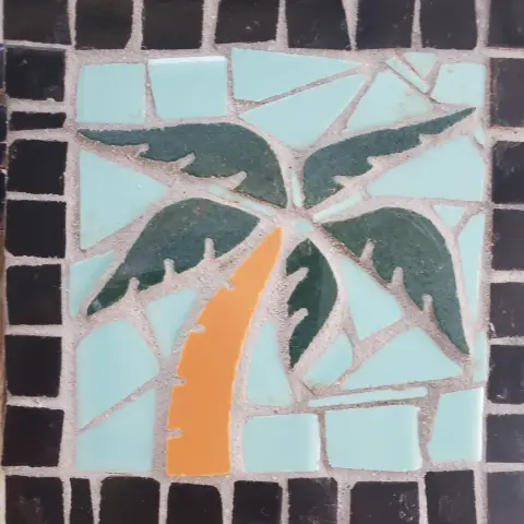 A mosaic tile of a palm tree in a black tiled border