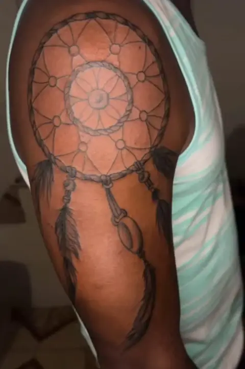 A dreamcatcher tattoo on an upper arm