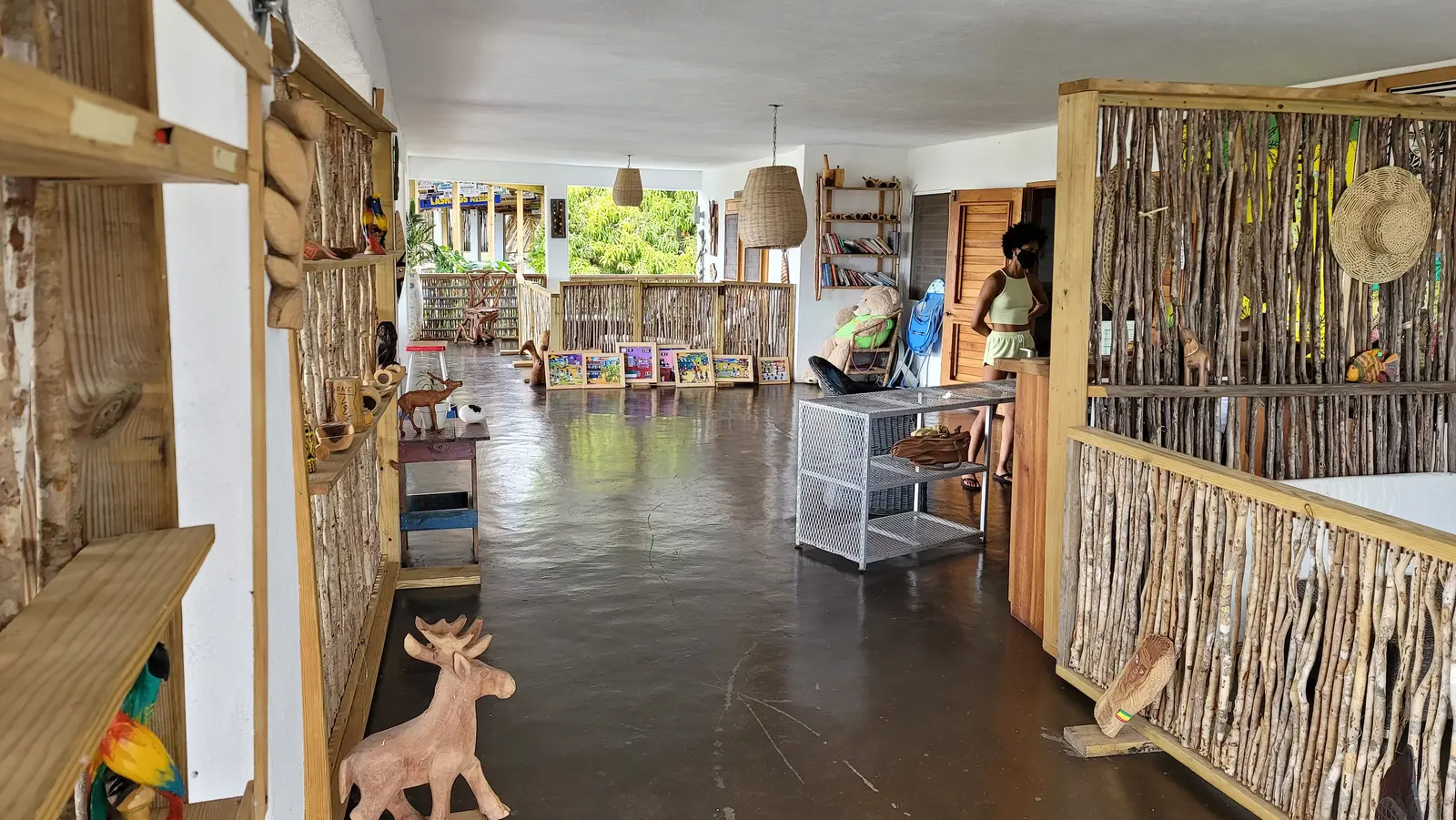 A wide, open room of carvings on shelves and paintings along the far wall, divided by stick screens