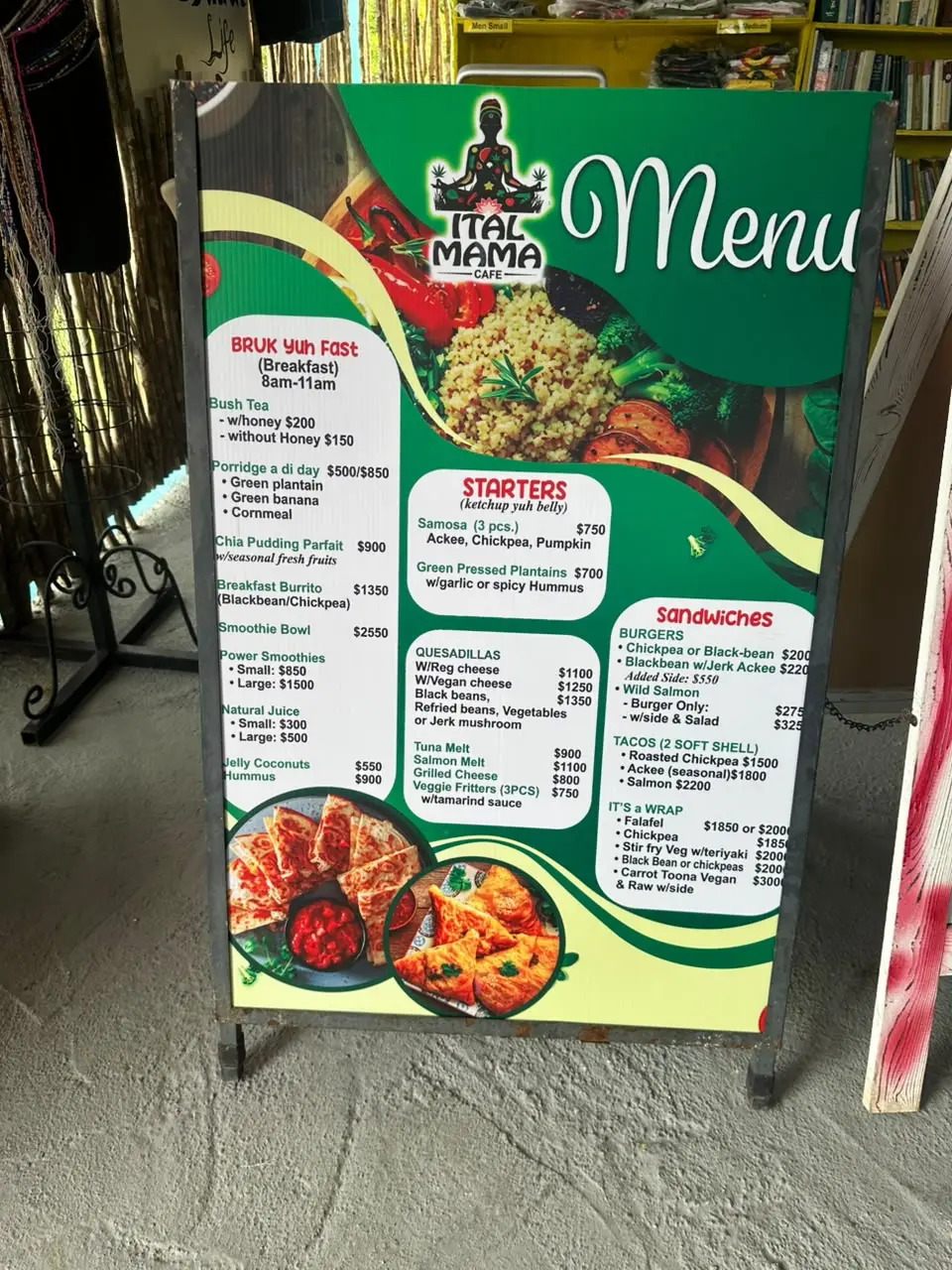The Ital Mama Café menu board, listing breakfast, starters, quesadillas, burgers, tacos and wraps with prices